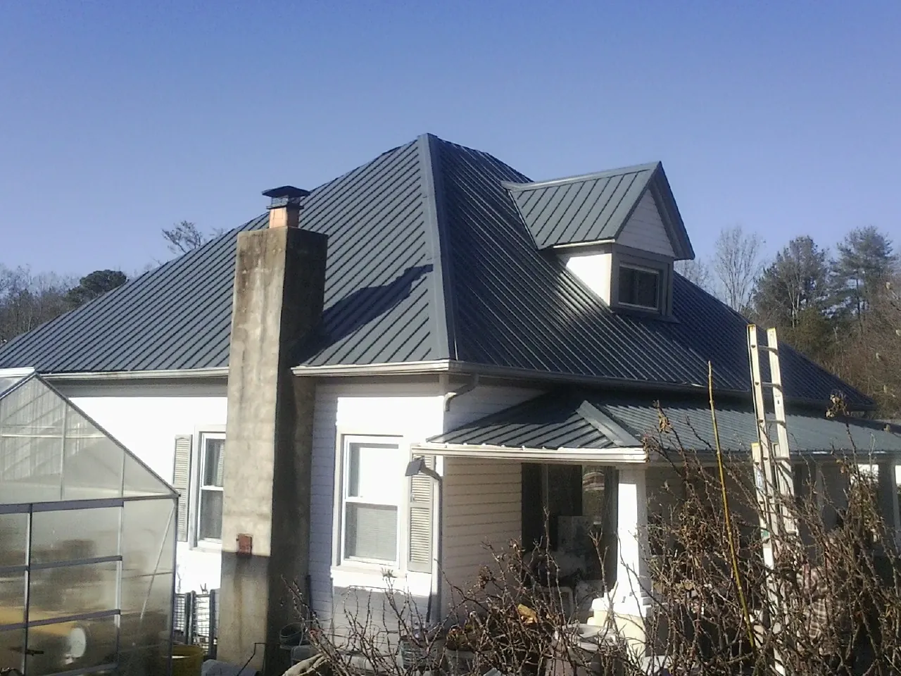 Dark blue standing seam metal roof on a white farmhouse with dormer — Slate & Tile Roof Repair by Roofing Brothers in Upperstrasburg