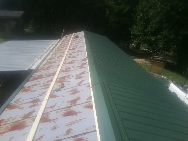 Old rusted panels beside newly installed green metal roofing — Wind Damage Roof Repair by Roofing Brothers in Upperstrasburg
