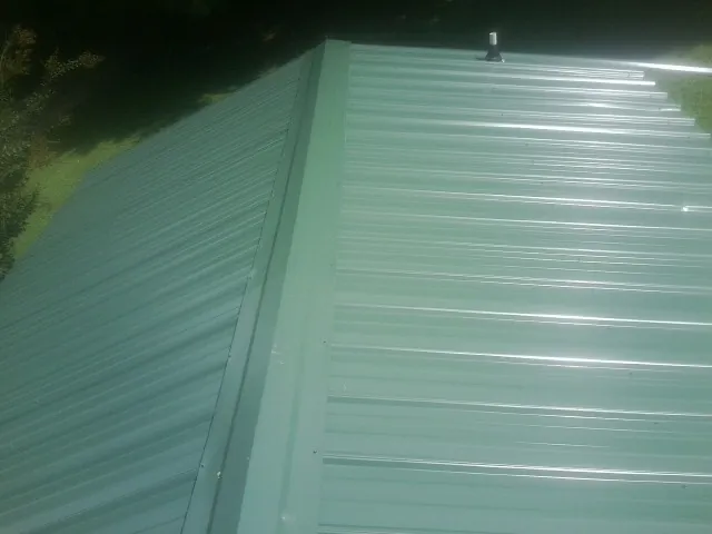New green metal panels meeting at the ridge of a roof — Flat Roof Repair work by our crew in Upperstrasburg