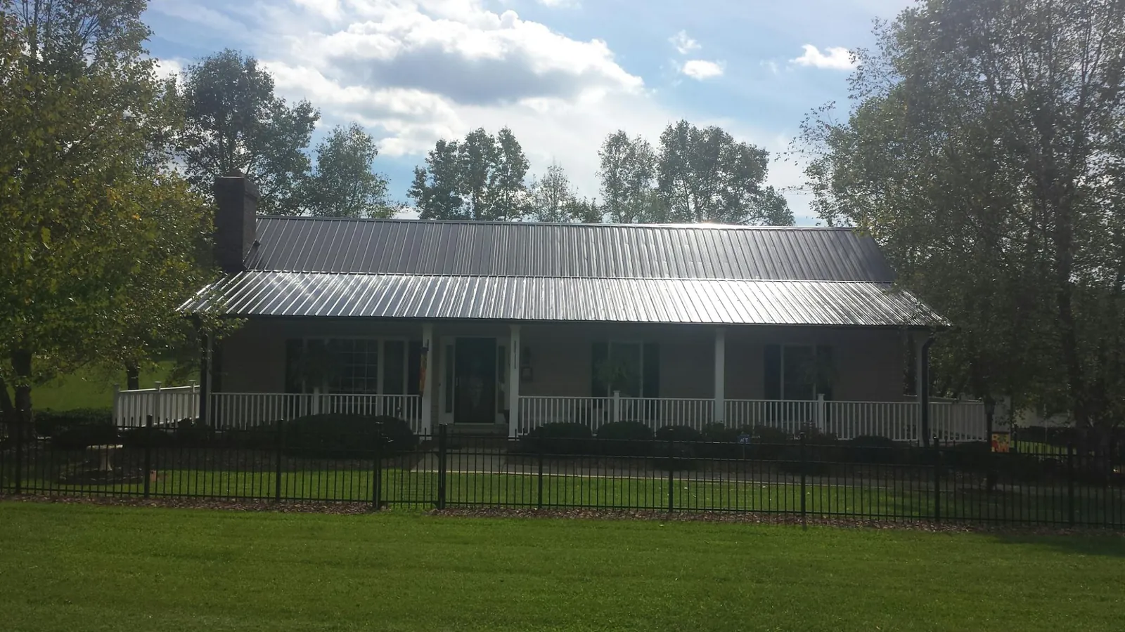 Gray metal roof on a brick ranch with a full width front porch — Gutter Guard Installation work by our crew in Upperstrasburg