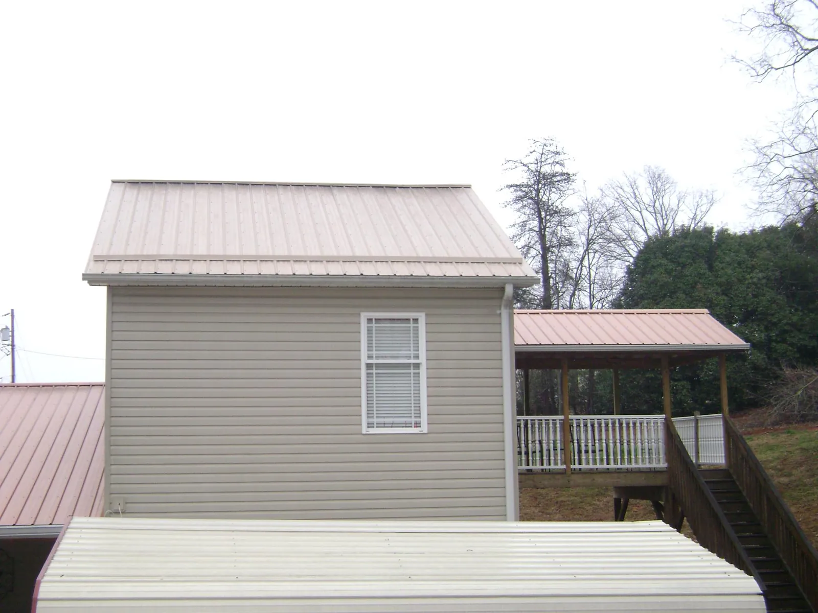 Tan metal roofs on a two story addition and attached porch, from a Roof Replacement job in Upperstrasburg
