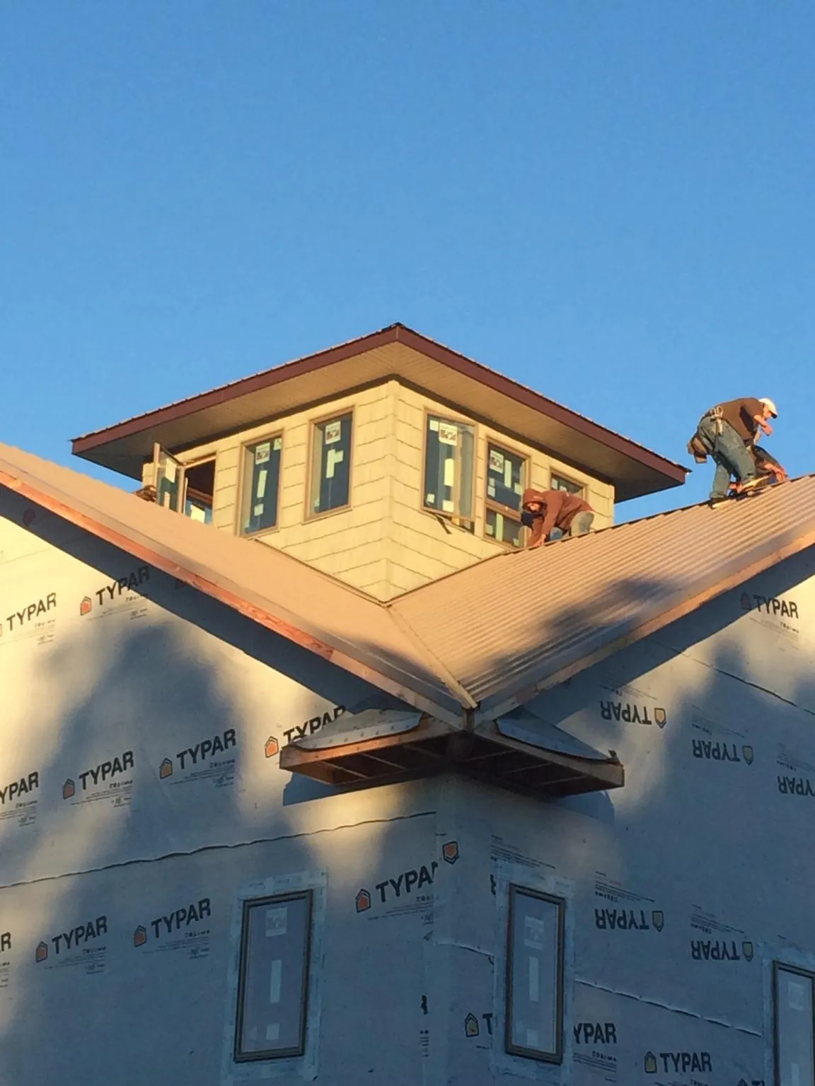 Roofers working around a rooftop cupola on a new metal roof at sunset — Roof Waterproofing in Upperstrasburg by Roofing Brothers